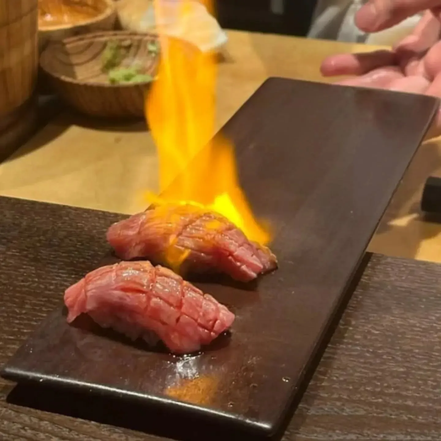 Nigiri seared to order with a flame at the counter.
