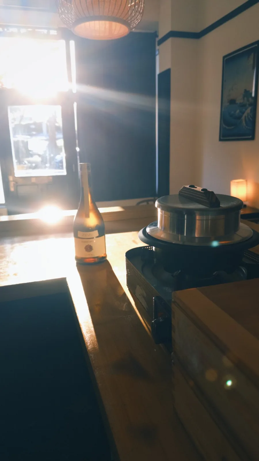 Late-afternoon sun across the counter, with sake and the rice pot.