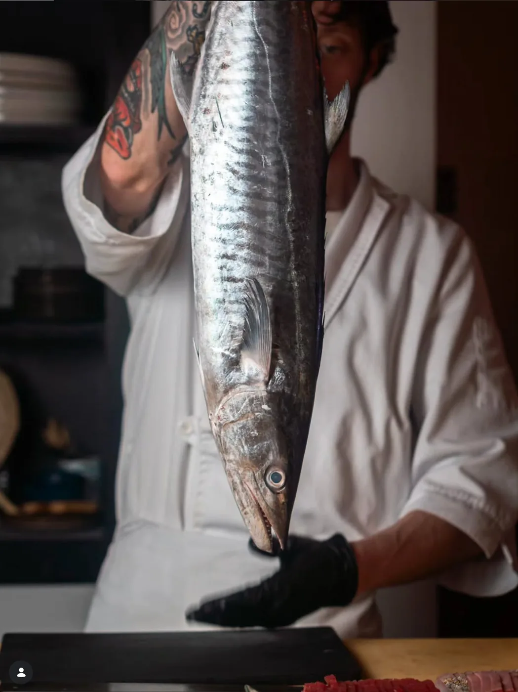 The chef holding a whole fish before breaking it down for the counter.